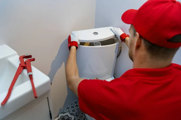 Servicios de fontanería - fontanero que trabaja en cuarto de baño instalación de inodoro tanque de agua wc —  Fotos de Stock