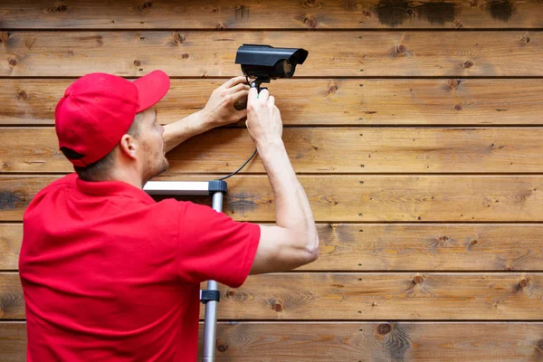 Охрана дома - человек устанавливает наружную камеру наблюдения на WO — стоковое фото
