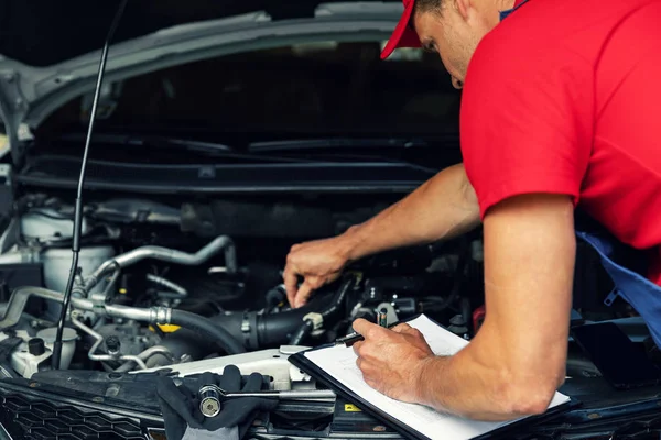 Manutenção do carro - mecânico verificar o motor e escrever na lista de verificação — Fotografia de Stock