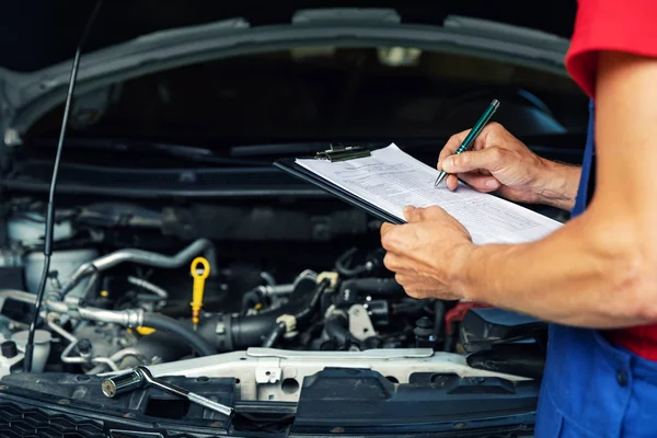 Car maintenance and repair - mechanic writing checklist paper on clipboard — Stock Photo, Image