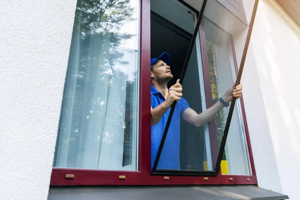 Hombre instalación de malla de alambre mosquitero en la ventana de la casa — Foto de Stock