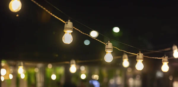 Luzes de corda de festa penduradas sobre terraço restaurante ao ar livre — Fotografia de Stock