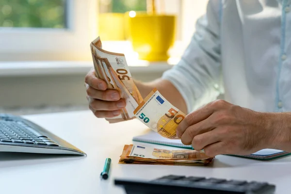 Hombre contando billetes de dinero en efectivo en euros sobre la mesa — Foto de Stock