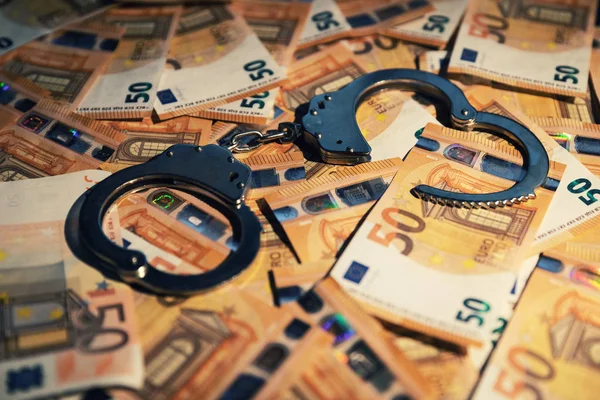 Концепция финансовых преступлений - наручники на наличные деньги — стоковое фото
