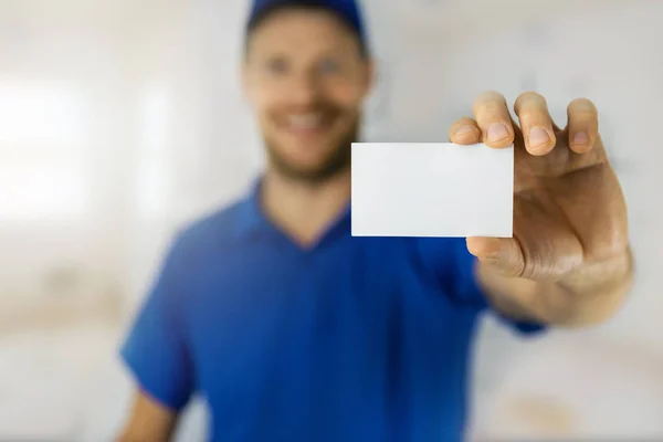 Manitas sonrientes en uniforme azul mostrando tarjeta de visita en blanco — Foto de Stock