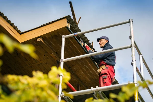 Worker on scaffolding renovating wooden roof structure — Stock Photo, Image