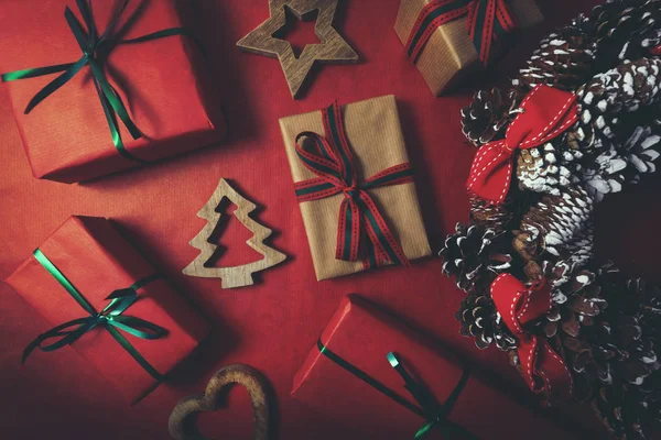 Χριστουγεννιάτικα δώρα και Χριστουγεννιάτικο στεφάνι σε φόντο κόκκινου χαρτιού — Φωτογραφία Αρχείου