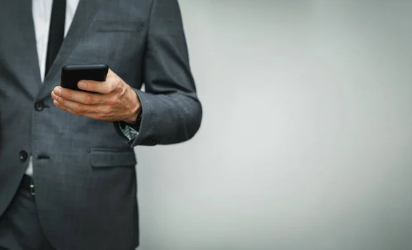Uomo d'affari che indossa tuta utilizzando il telefono su sfondo grigio. copia spazio — Foto Stock