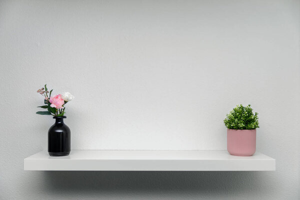 wooden shelf on white wall with green plant flower vase