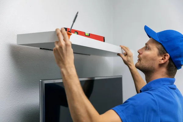 Faz-tudo instalando prateleira na parede em casa — Fotografia de Stock