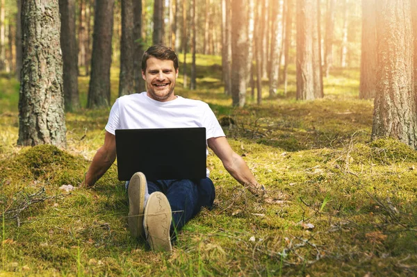Junger Lächelnder Mann Sitzt Moos Und Benutzt Laptop Wald — Stockfoto