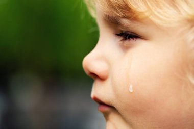 Ağlayan üzgün çocuk. Yanağında gözyaşı olan küçük kız yüzü. Çocuk hakları ve istismar kavramı