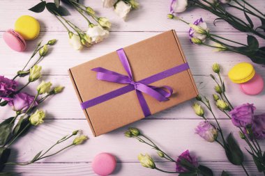 Çiçekli hediye kutusu ve beyaz ahşap arka planda badem kurabiyesi. Doğum günü için tebrik kartı, anneler günü ya da sevgililer günü