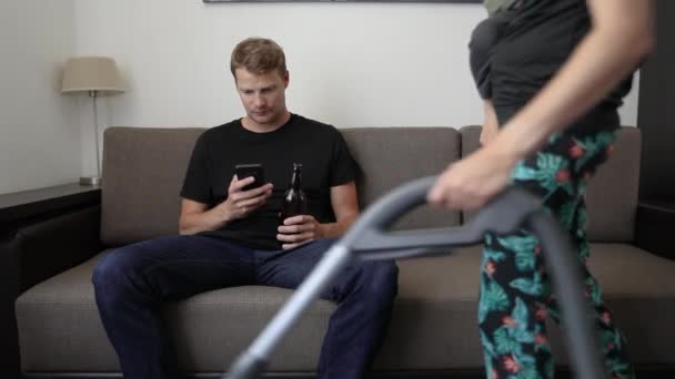 Τεμπέλης Σύζυγος Κάθεται Στον Καναπέ Χρησιμοποιώντας Τηλέφωνο Και Πίνοντας Μπύρα — Αρχείο Βίντεο