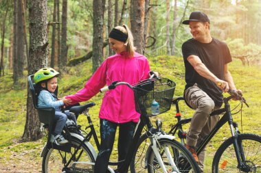 Ormanda bisiklet sürerken, bisikletli çocuk koltuğunda genç mutlu bir aile. aktif spor açık hava eğlencesi