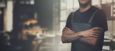 Kahve dükkanında kolları kavuşturulmuş bir barista. Boşluğu kopyala