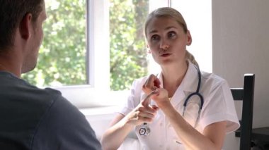 Doktor ziyareti. Genç kadın hekim, hastane ofisindeki hastaya tavsiye veriyor.