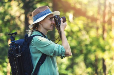 Kadın fotoğrafçı, ormanda analog film kamerasıyla doğanın fotoğrafını çekiyor.