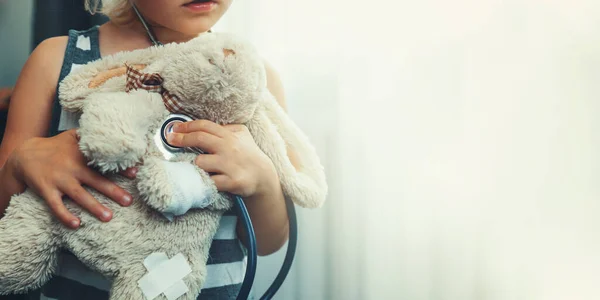 柔らかいおもちゃで医者をしている子供です ウサギを聴診器で調べる少女 コピースペース — ストック写真
