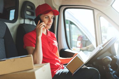 Karavanda cep telefonuyla konuşan teslimatçı kadın.
