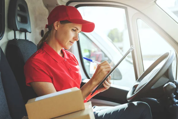 Zustellerin Roter Uniform Sitzt Lieferwagen Und Schreibt Dokumente — Stockfoto