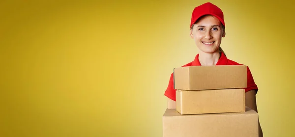 Servicio Entrega Joven Repartidor Sonriente Uniforme Rojo Sosteniendo Cajas Cartón —  Fotos de Stock