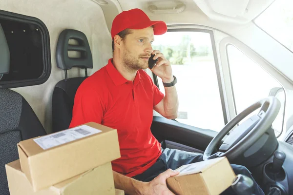 package delivering - delivery man using mobile phone while sitting in van
