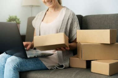 Evden satıyorum. Küçük işletme girişimcisi kadın çevrimiçi mağazadan taşınmak için posta kutusunu kontrol edip paketliyor