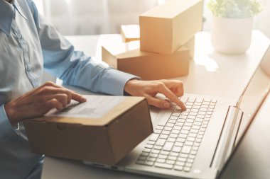 Kişi dizüstü bilgisayar kullanarak çevrimiçi mağaza siparişleri hazırlıyor