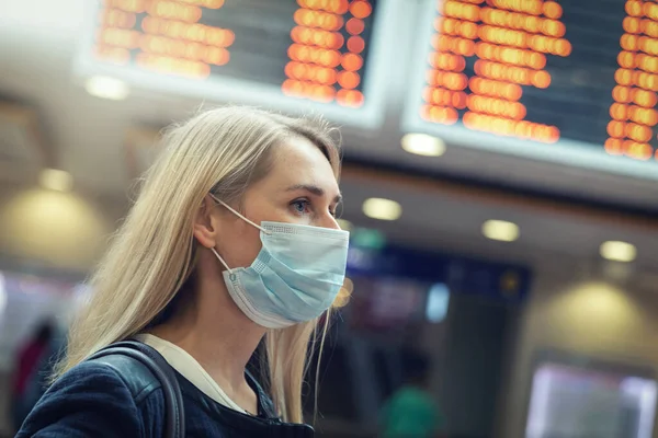 woman wearing protective face mask at crowded train station during virus pandemic
