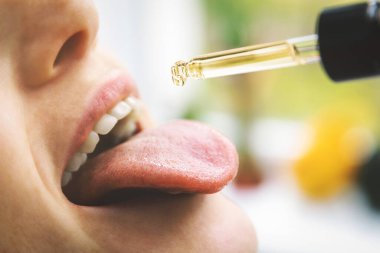 herbal alternative medicine and dietary supplements - woman taking cbd hemp oil drops in mouth from dropper. medical cannabis clipart