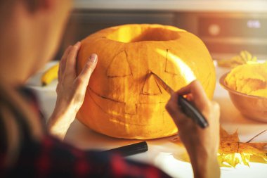 Cadılar Bayramı için ev mutfağında balkabağını balkabağına oyan kadın.