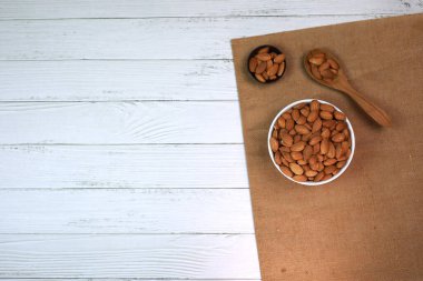 Beyaz ahşap zemindeki bademler parlak ve güzel bir kahvaltı için mükemmeldir..