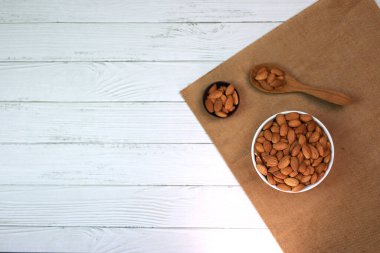 Beyaz ahşap zemindeki bademler parlak ve güzel bir kahvaltı için mükemmeldir..