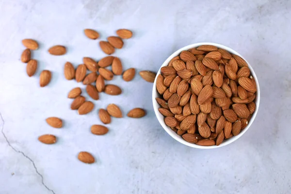 Beyaz ahşap zemindeki bademler parlak ve güzel bir kahvaltı için mükemmeldir..