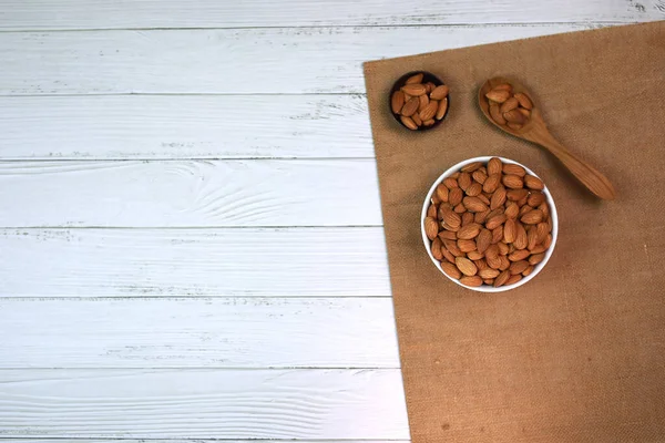 Beyaz ahşap zemindeki bademler parlak ve güzel bir kahvaltı için mükemmeldir..