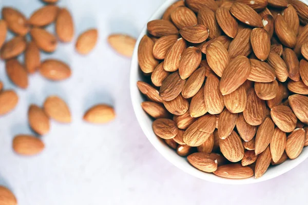 Beyaz ahşap zemindeki bademler parlak ve güzel bir kahvaltı için mükemmeldir..