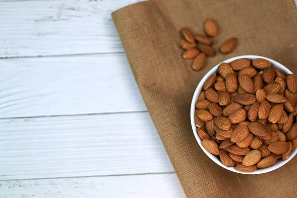 Beyaz ahşap zemindeki bademler parlak ve güzel bir kahvaltı için mükemmeldir..