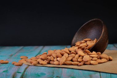 Bardakta badem, ahşap bir zeminde, siyah bir arka planda, yemek pişirmek için uygun.