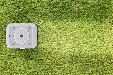 3D render robot elektrik süpürgesi üzerinde yeşil halı üstten görünüm