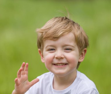 Parkta eğleniyor ve gülümseyen mutlu küçük çocuk