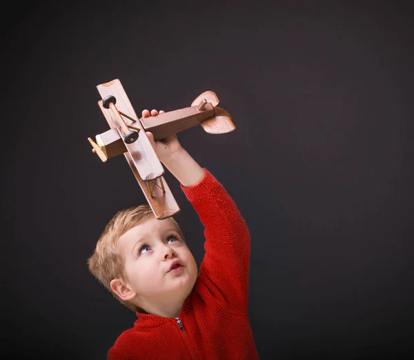 Glücklicher Junge Spielt Mit Holzflugzeug Auf Schwarzem Hintergrund — Stockfoto