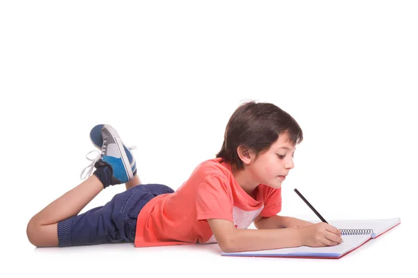 School jongen liggend op de vloer en tekenen met potlood, geïsoleerd op een — Stockfoto