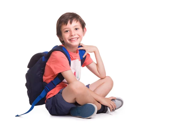 Feliz menino da escola sorrindo sentado no chão, isolado em um wh Fotografias De Stock Royalty-Free
