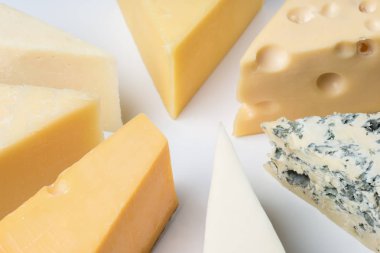 Peynirler üçgenler beyaz bir kağıt üzerinde büyük bir çeşitlilik