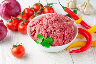 Bir beyaz plaka ve taze domates, biber, soğan, sarımsak rustik masa yakın çekim üzerinde çiğ kıyılmış domuz. üstten görünüm