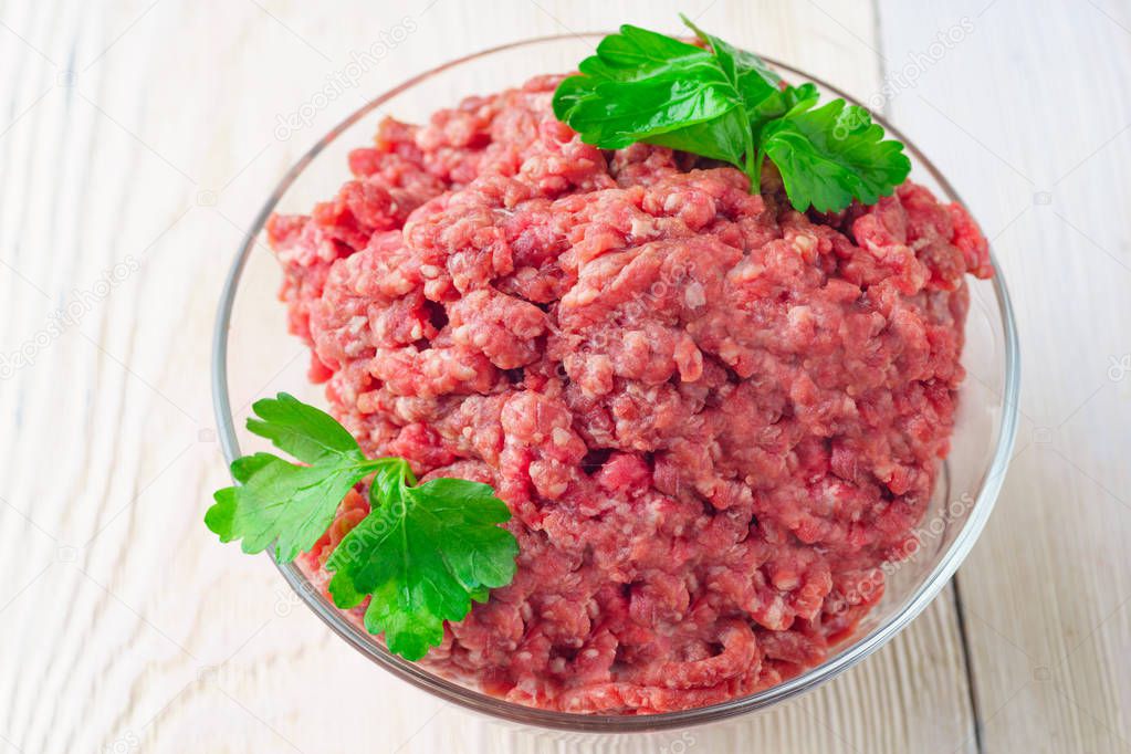 Meat stuffing for cutlets or meatballs in a glass bowl on a white table. The concept: food, cooking, burgers. Copy space. Chopped meat