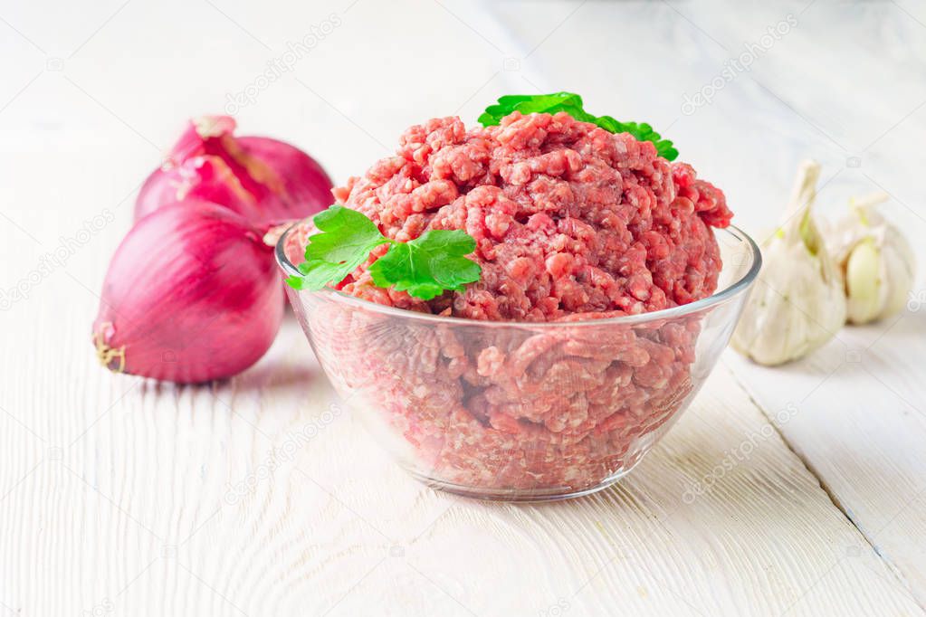 Meat stuffing for cutlets or meatballs in a glass bowl on a white table. The concept: food, cooking, burgers. Copy space. Chopped meat