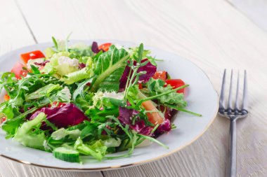 Taze salata yeşil ve mor marul, domates ve salatalık Beyaz ahşap zemin üzerine kapatın. Sağlıklı gıda.