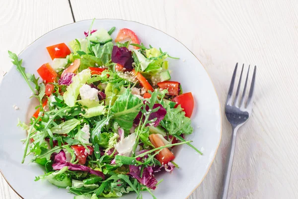 Taze salata yeşil ve mor marul, domates ve salatalık Beyaz ahşap zemin üzerine kapatın. Sağlıklı gıda.